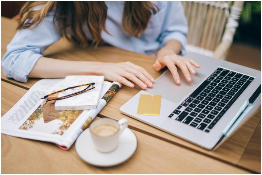 Woman working on a laptop with coffee and a magazi