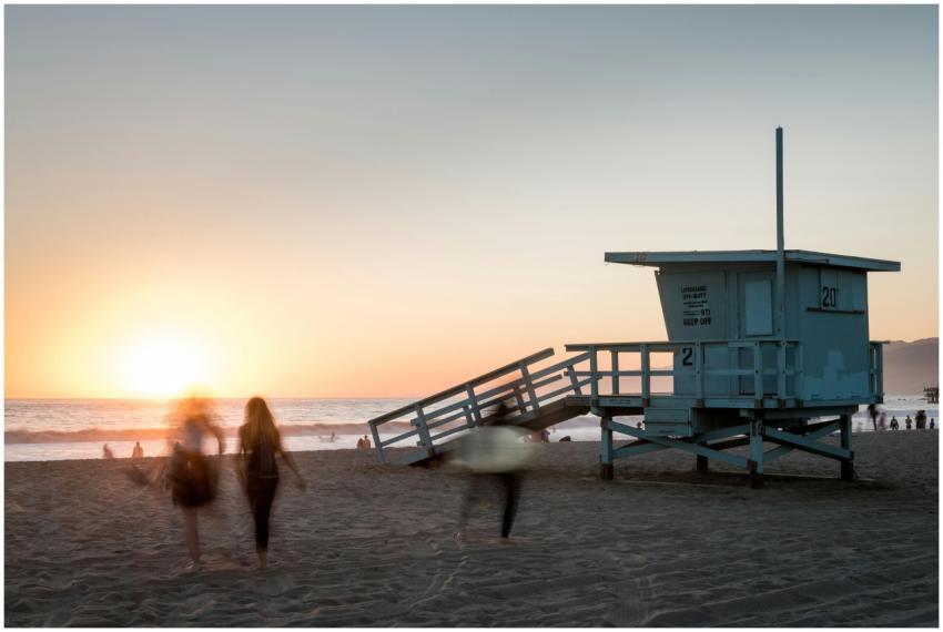 Beach scene at sunset with a lifeguard tower and p