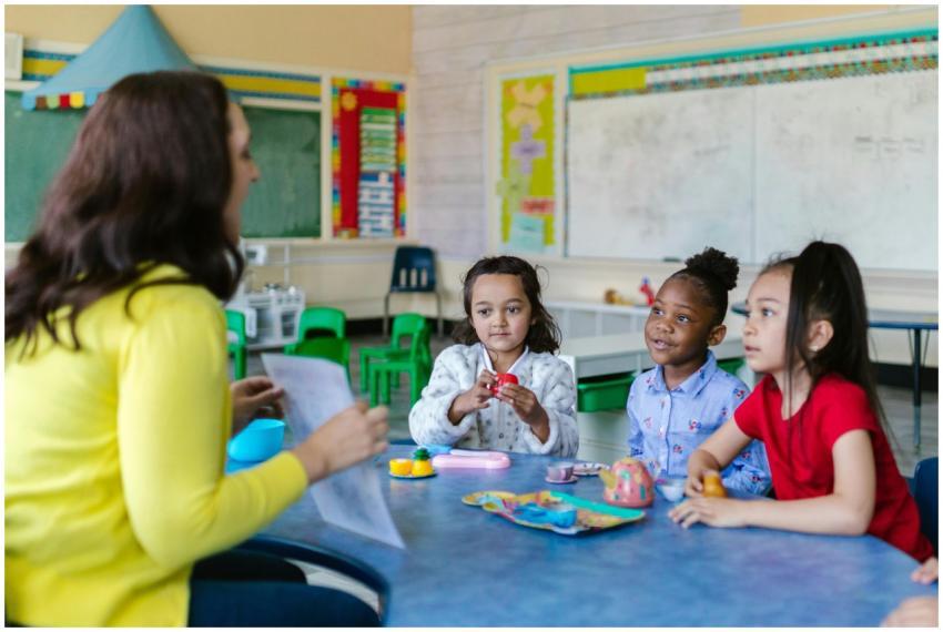 Three diverse young girls engage with a teacher in