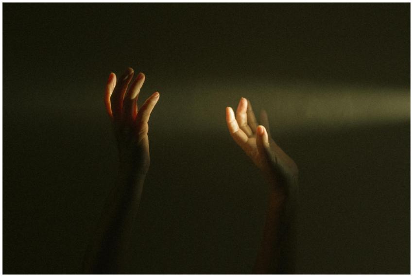 Expressive hands reaching towards a ray of light s