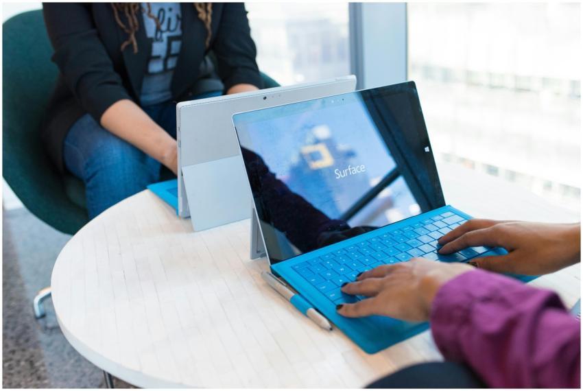 Two people using modern laptops in a bright office