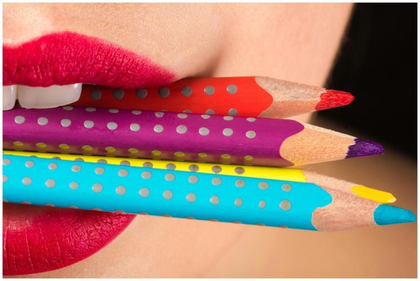 Close-up of red lips gently holding colorful dotte