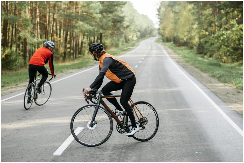 Two cyclists wearing helmets and sportswear biking