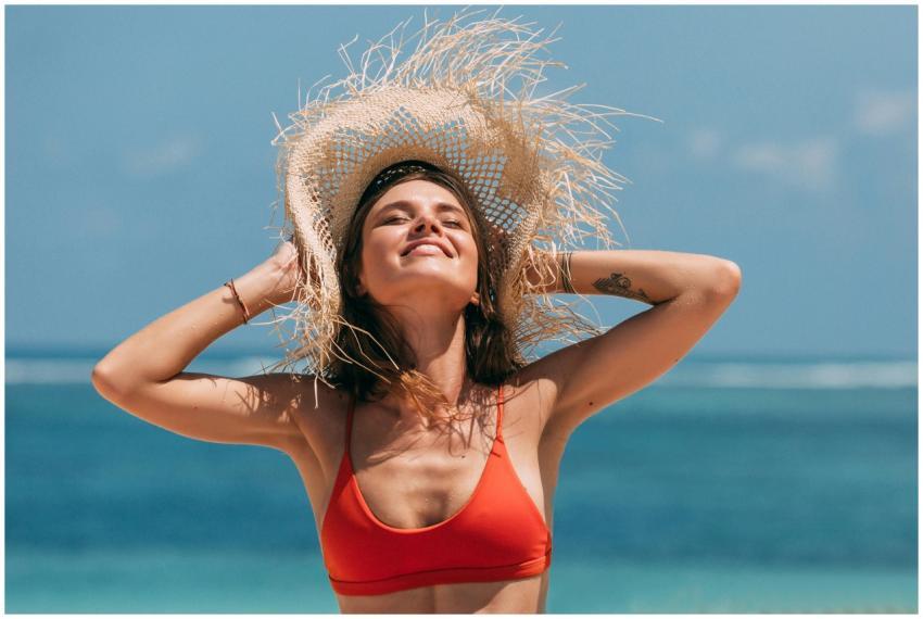 Young woman in red bikini top and straw hat enjoyi