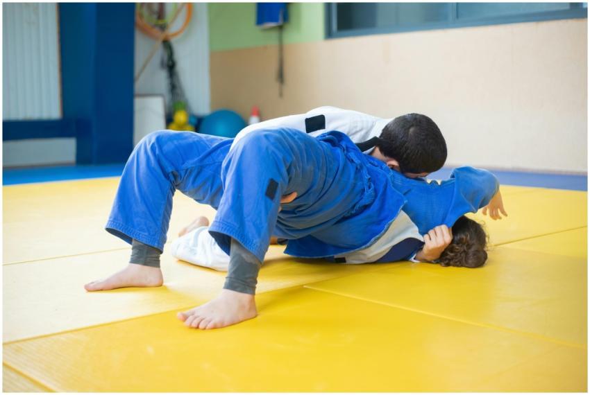 Two children practice judo in a dojo, showcasing m