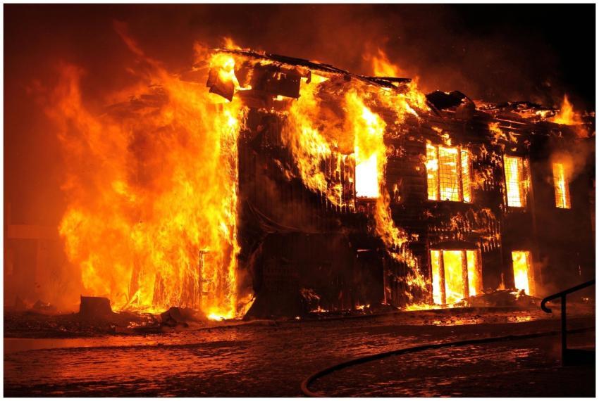 A dramatic nighttime scene of a house engulfed in
