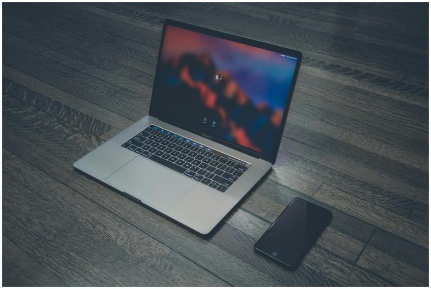 A sleek laptop and smartphone placed on wooden flo