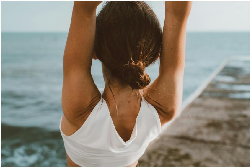 Back view of a woman meditating with raised hands
