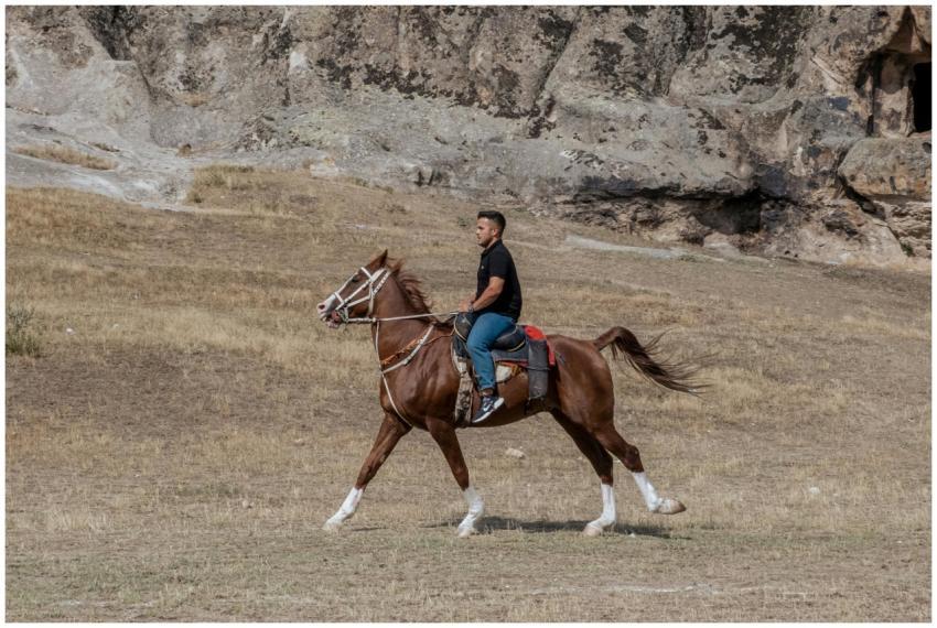 A man riding a brown horse in the scenic outdoors