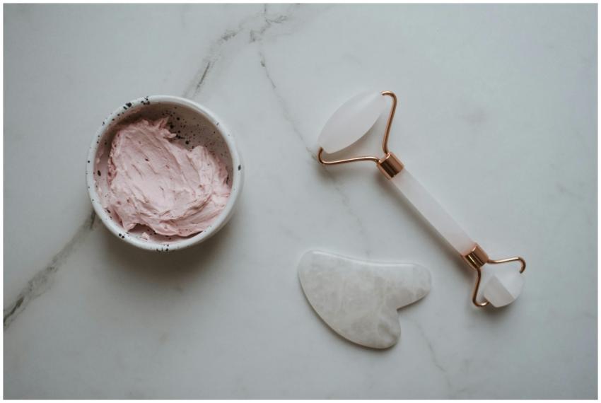 Top view of gua sha tools and pink facial cream on