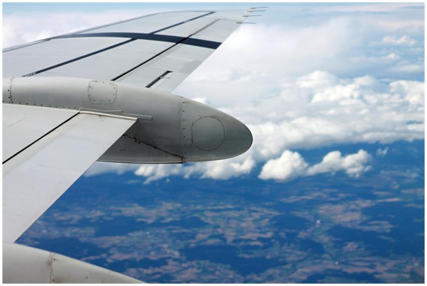 View of an airplane wing flying over clouds and la
