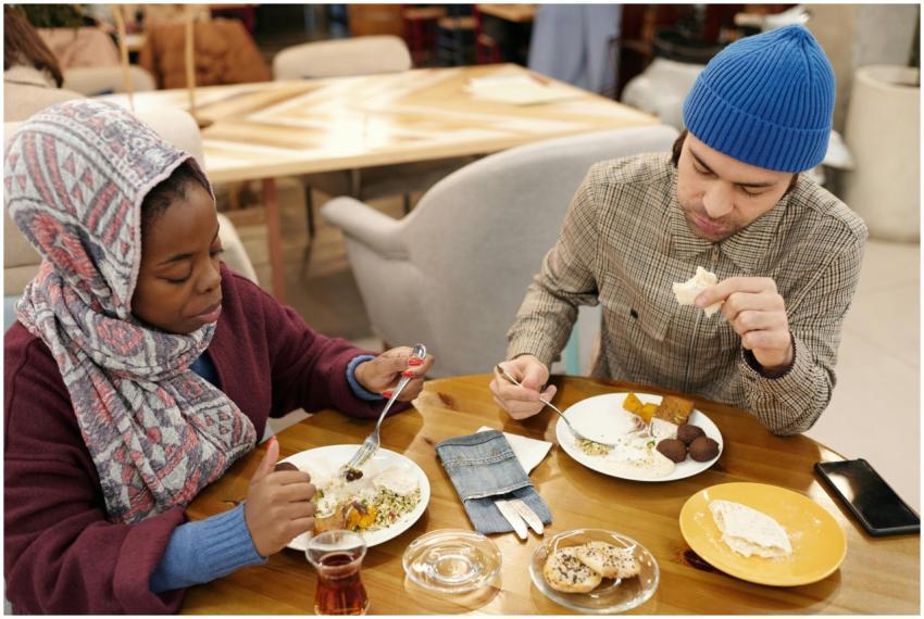 A multiethnic couple dining indoors, enjoying a Mi