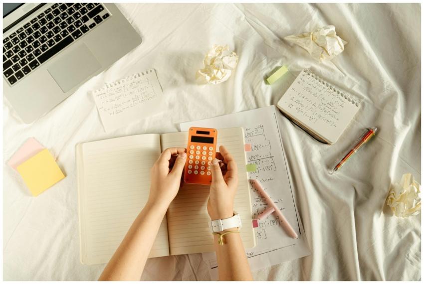 Flat lay of hands with orange calculator, notes, a