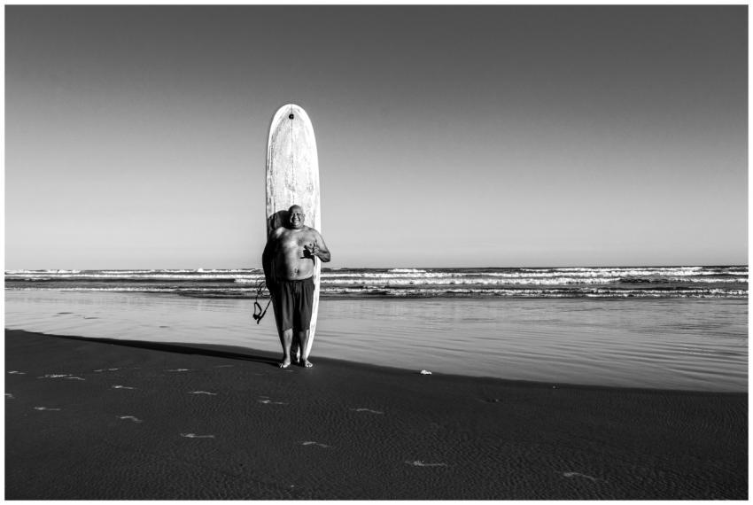 Black and white photo of a man with a surfboard on