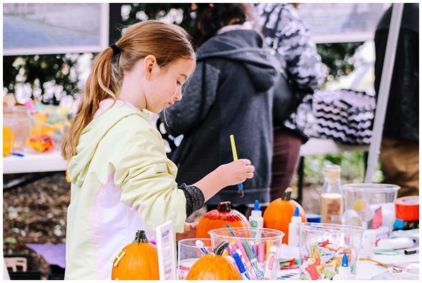 A child enjoys painting pumpkins at an outdoor cra