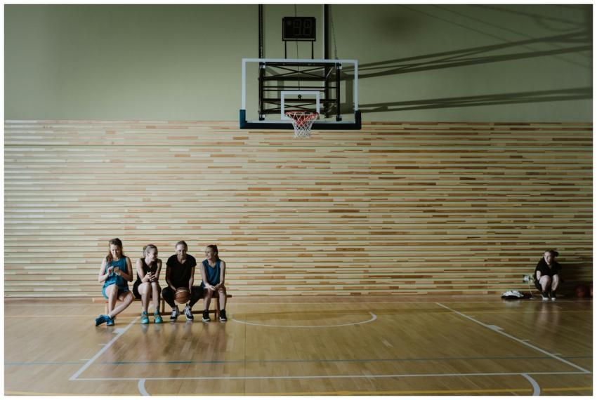 Young female basketball players sitting on a gym b