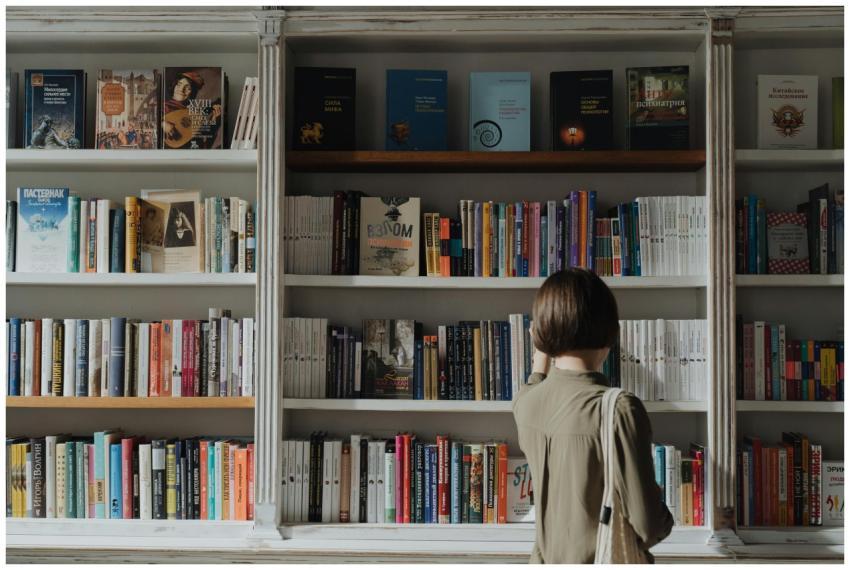 A woman browsing a large book collection in a cozy