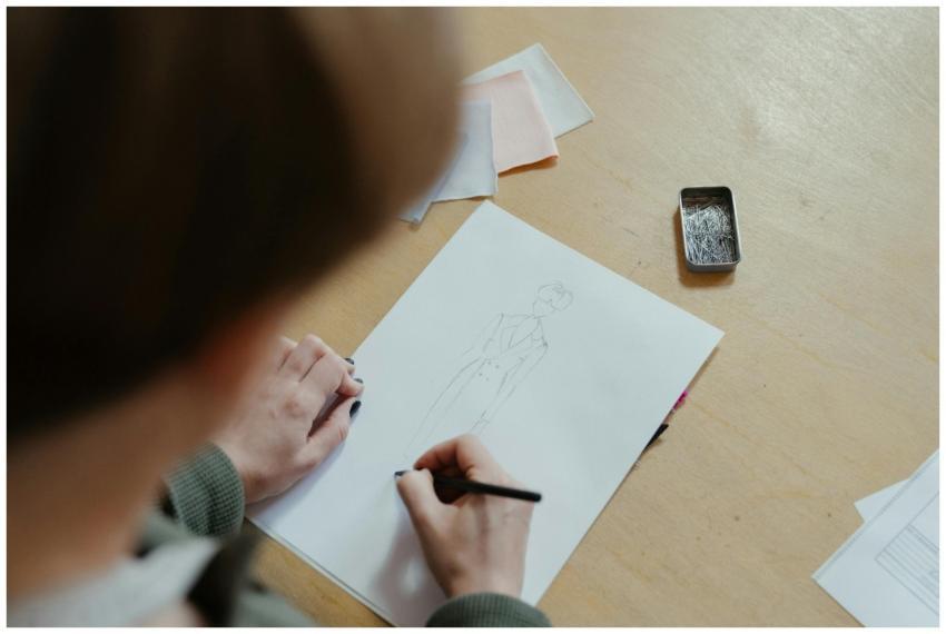 A person sketching fashion designs in a sewing wor