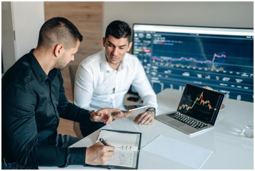 Two businessmen analyzing financial data on digita