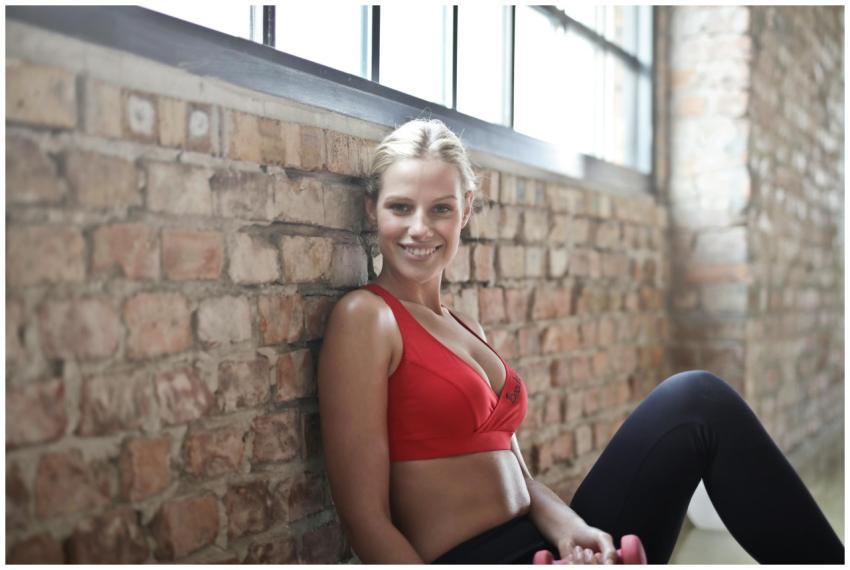 A fit woman in a red sports bra smiling while sitt