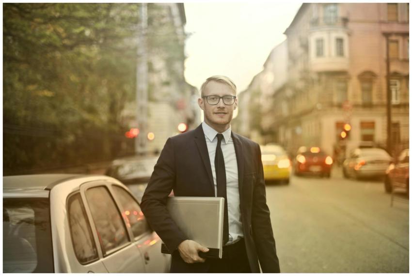 Businessman in a suit holding a laptop on a busy c