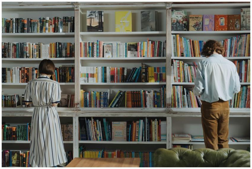 Two people browsing books in a cozy library, searc