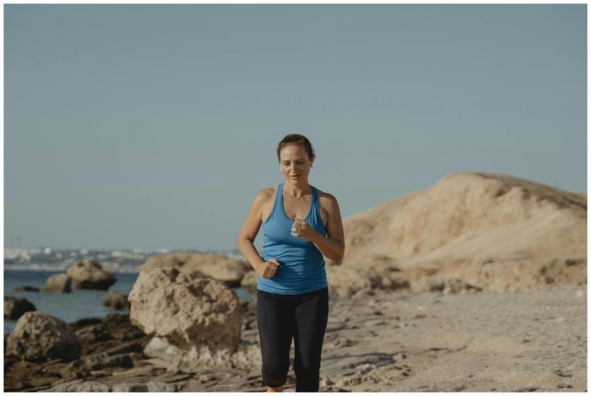 Woman jogging on a rocky beach path, promoting fit
