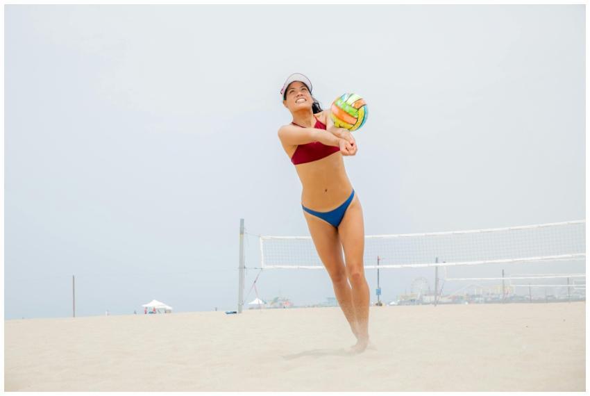 A woman playing beach volleyball on a sunny day, s