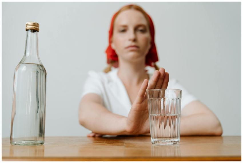 A woman with a red kerchief rejects a glass of alc
