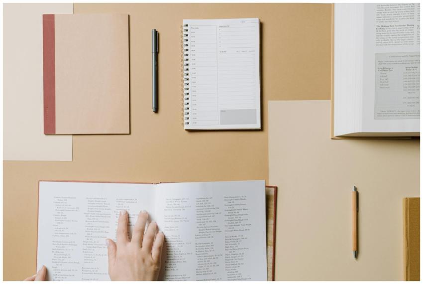 A top view of books and stationery on a beige desk