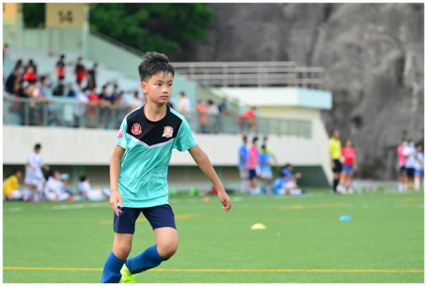 A young boy playing soccer outdoors in a sports fi