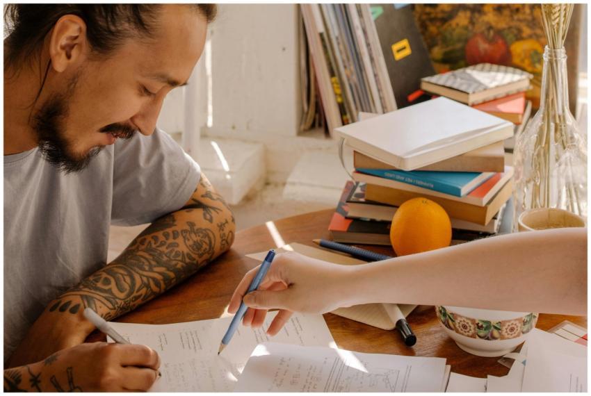 A tattooed Asian student concentrates on studying