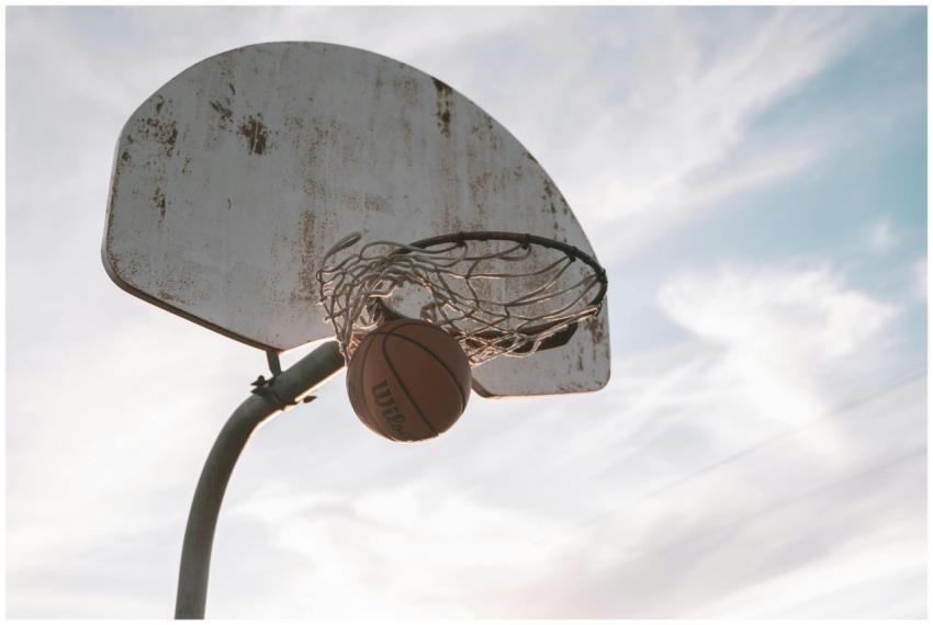 Basketball sinking into hoop against a dramatic bl