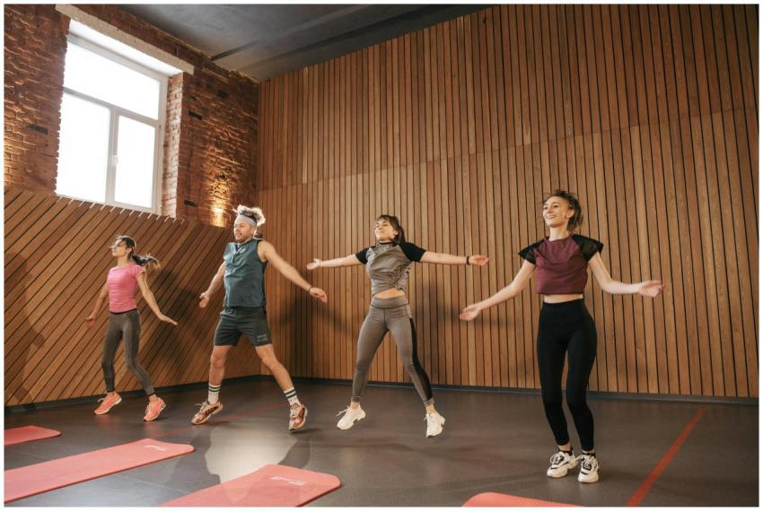 Group of adults doing jumping jacks in modern gym
