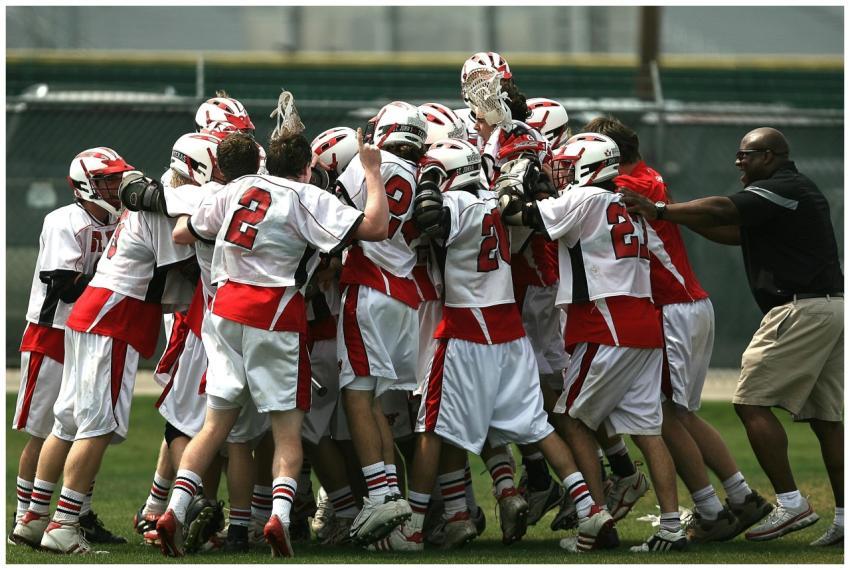 A group of lacrosse players and their coach celebr