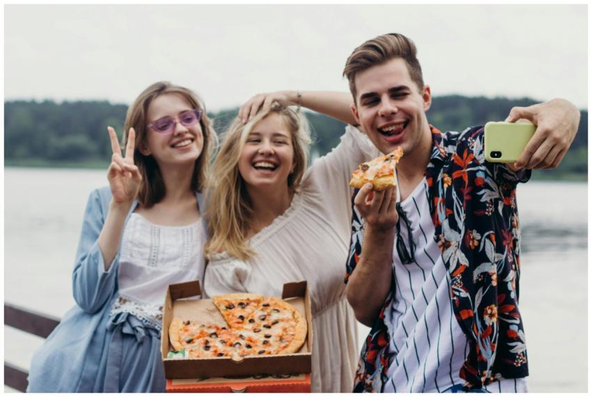 Group of friends enjoying pizza and taking a selfi