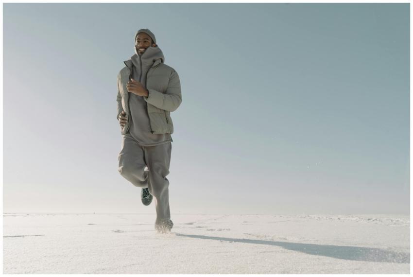 A man in a puffer jacket runs outdoors on a snowy
