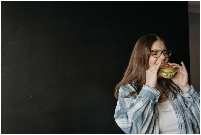 Woman in casual attire eating a hamburger in front