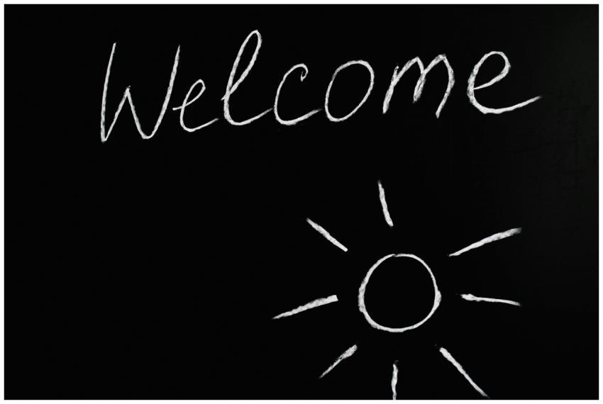Chalk-drawn 'Welcome' and sun illustration on a bl