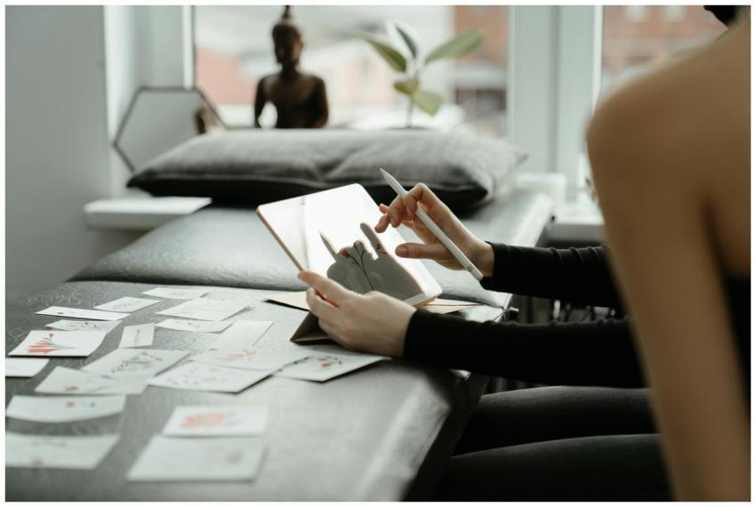 A person sketching tattoo designs on a tablet surr