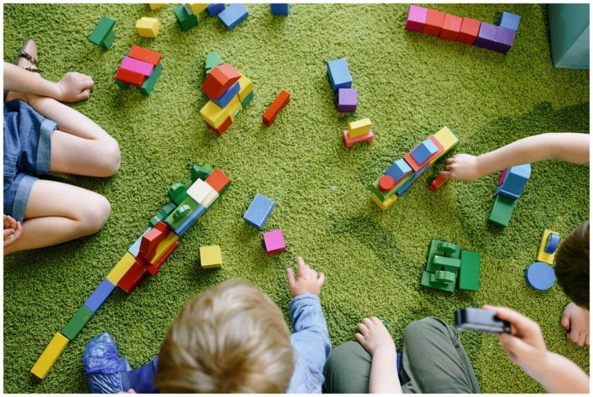 Children playing with wooden blocks on a green car