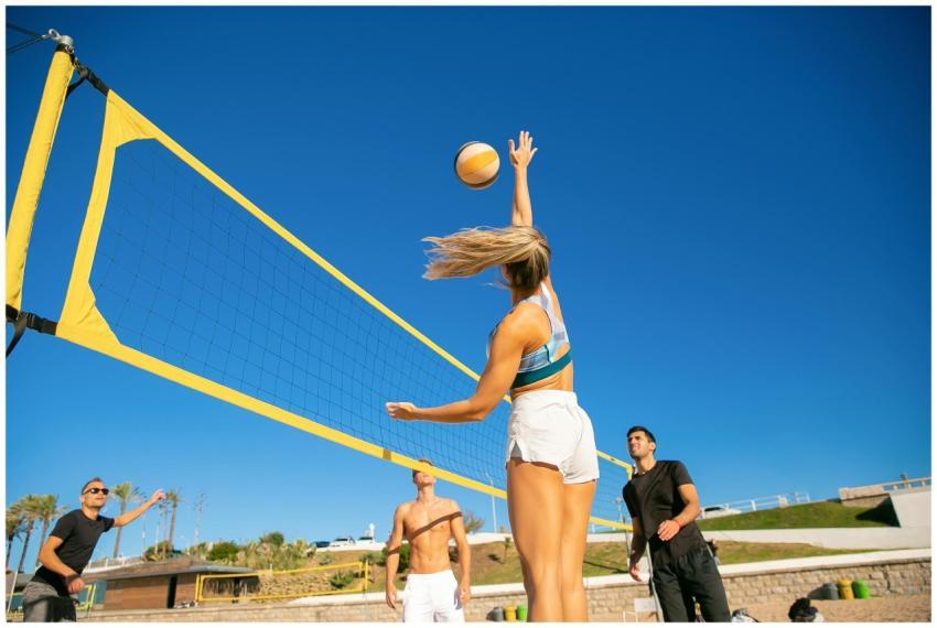Group of adults playing beach volleyball under a b