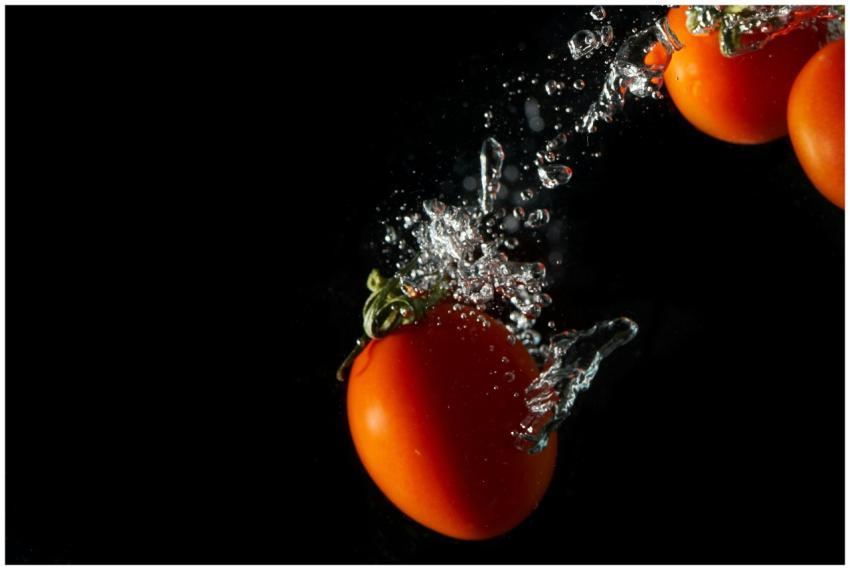 Vibrant tomatoes splashing underwater, set against