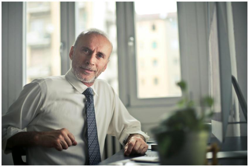 A mature man in professional attire smiling in an