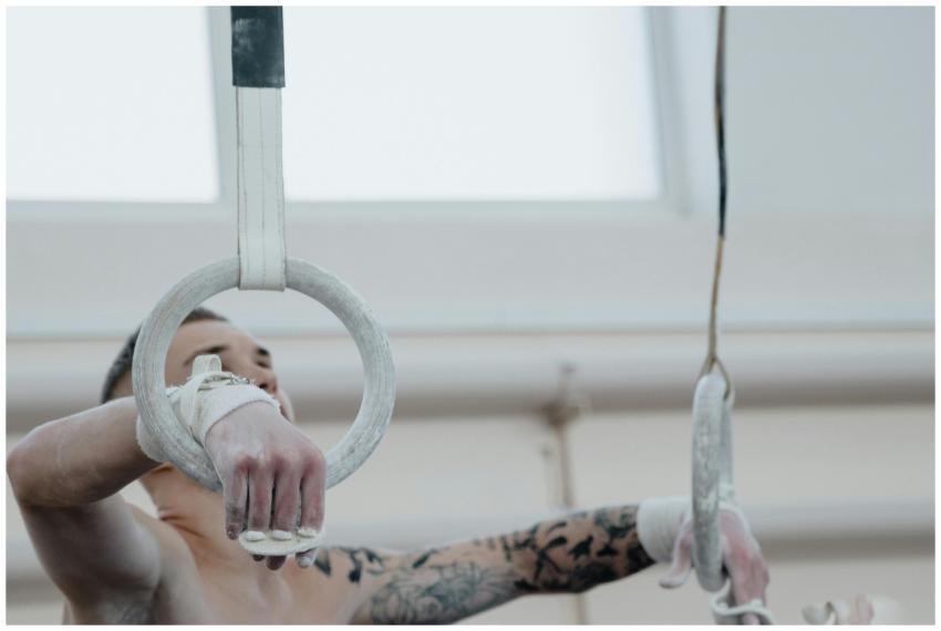 Close-up of a gymnast with tattooed arm holding gy