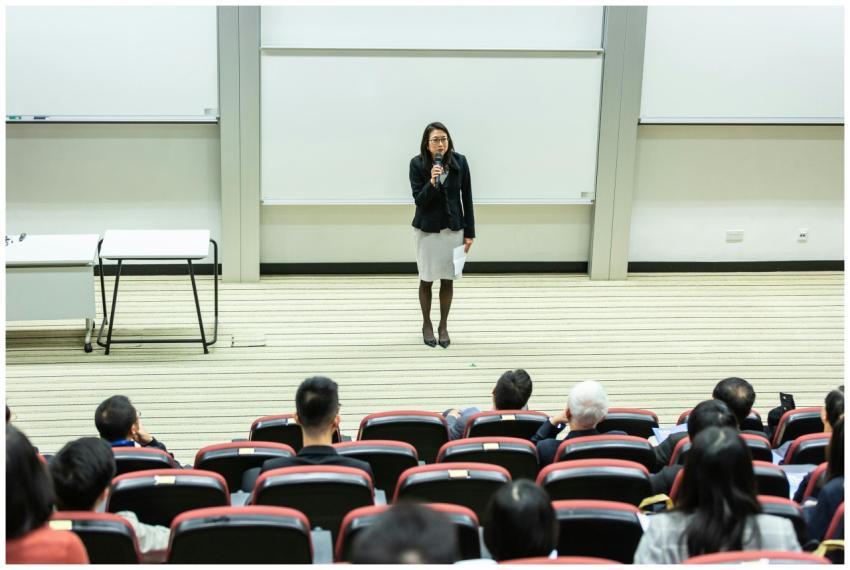 Female speaker presenting to an audience in a mode