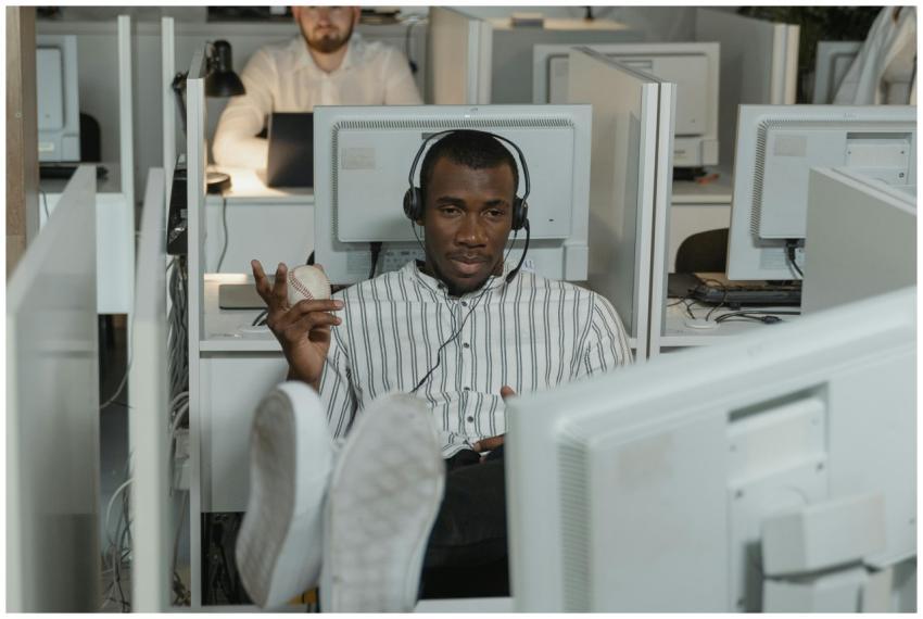 Man relaxing in office cubicle wearing headphones,