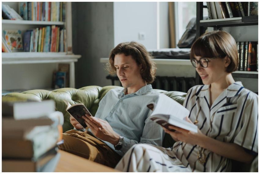 A man and woman relax on a couch reading in a cozy