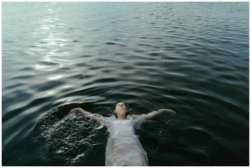 A woman peacefully floating in calm water, exuding