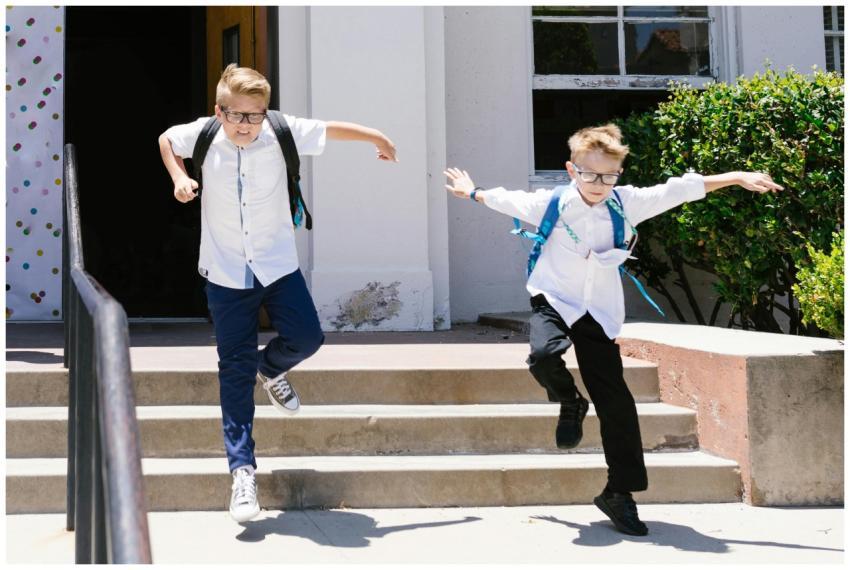 Two boys with backpacks energetically jumping down